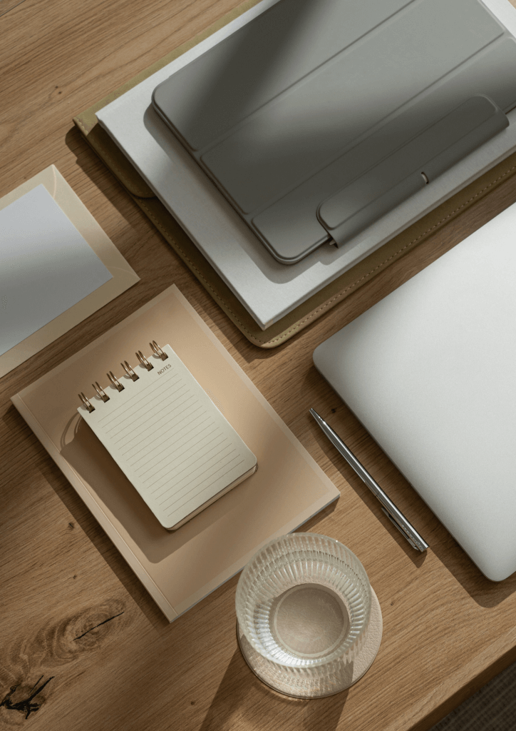 Photo vue du haut d'un bureau avec une tablette, un bloc note et un verre d'eau